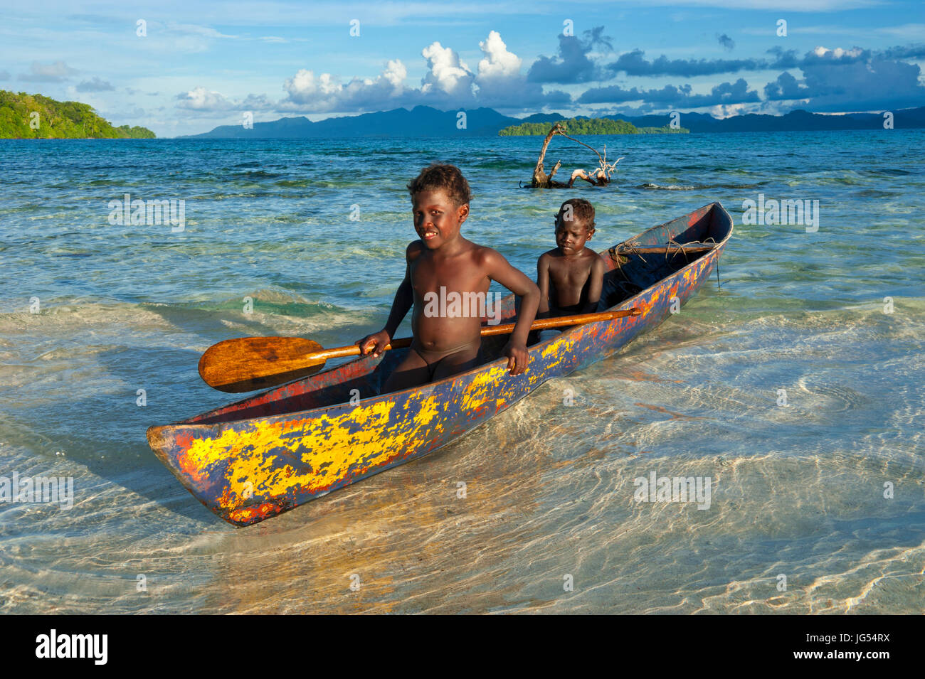 Young boys fishing in the Marovo Lagoon before dramatic clouds, Salomon Islands, Pacific Stock Photo