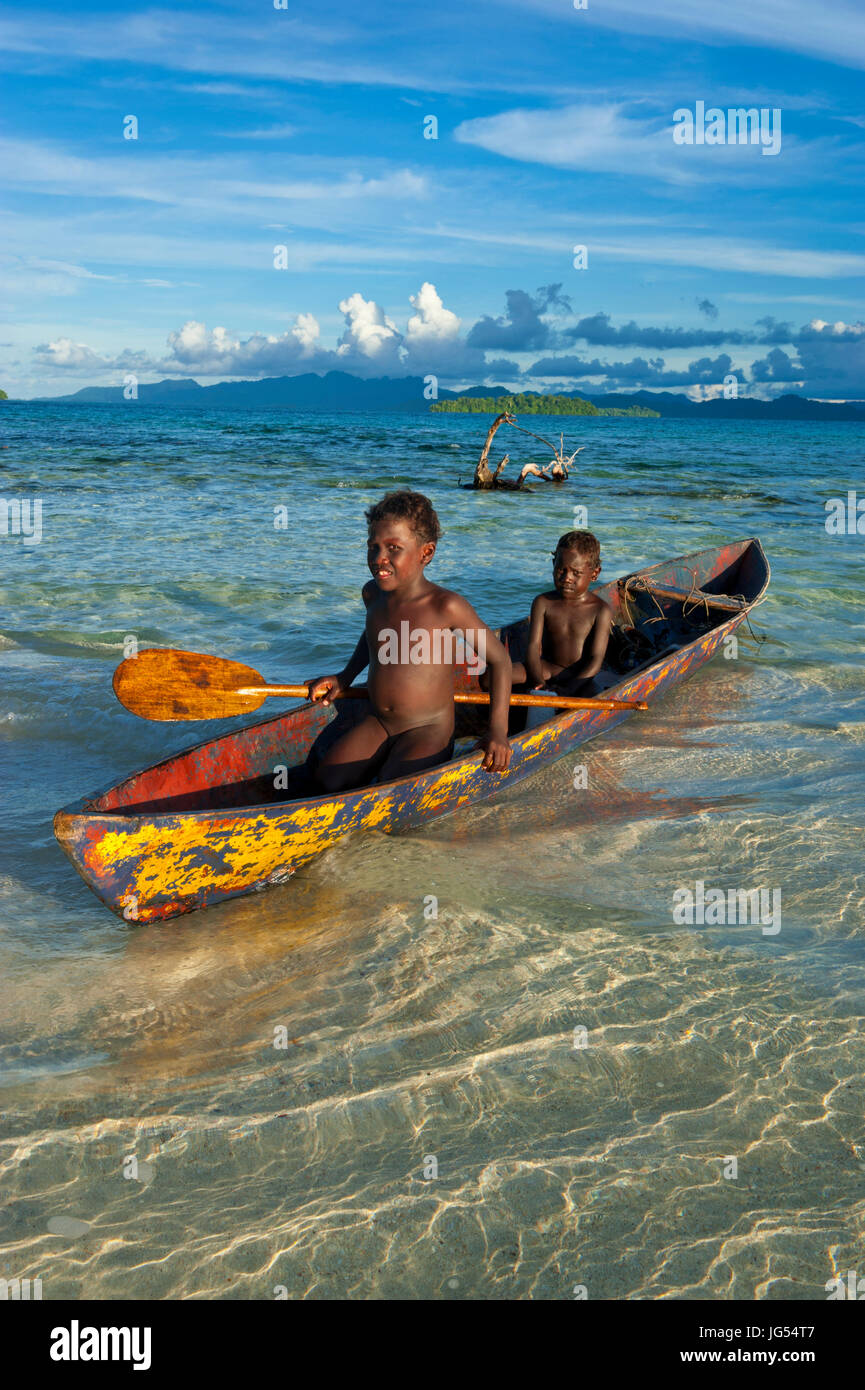 Young boys fishing in the Marovo Lagoon before dramatic clouds, Salomon Islands, Pacific Stock Photo