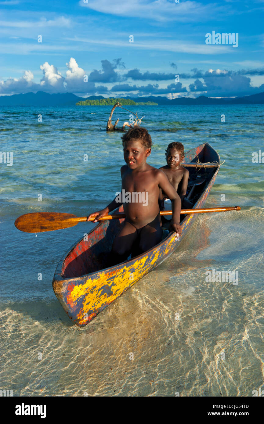 Young boys fishing in the Marovo Lagoon before dramatic clouds, Salomon Islands, Pacific Stock Photo