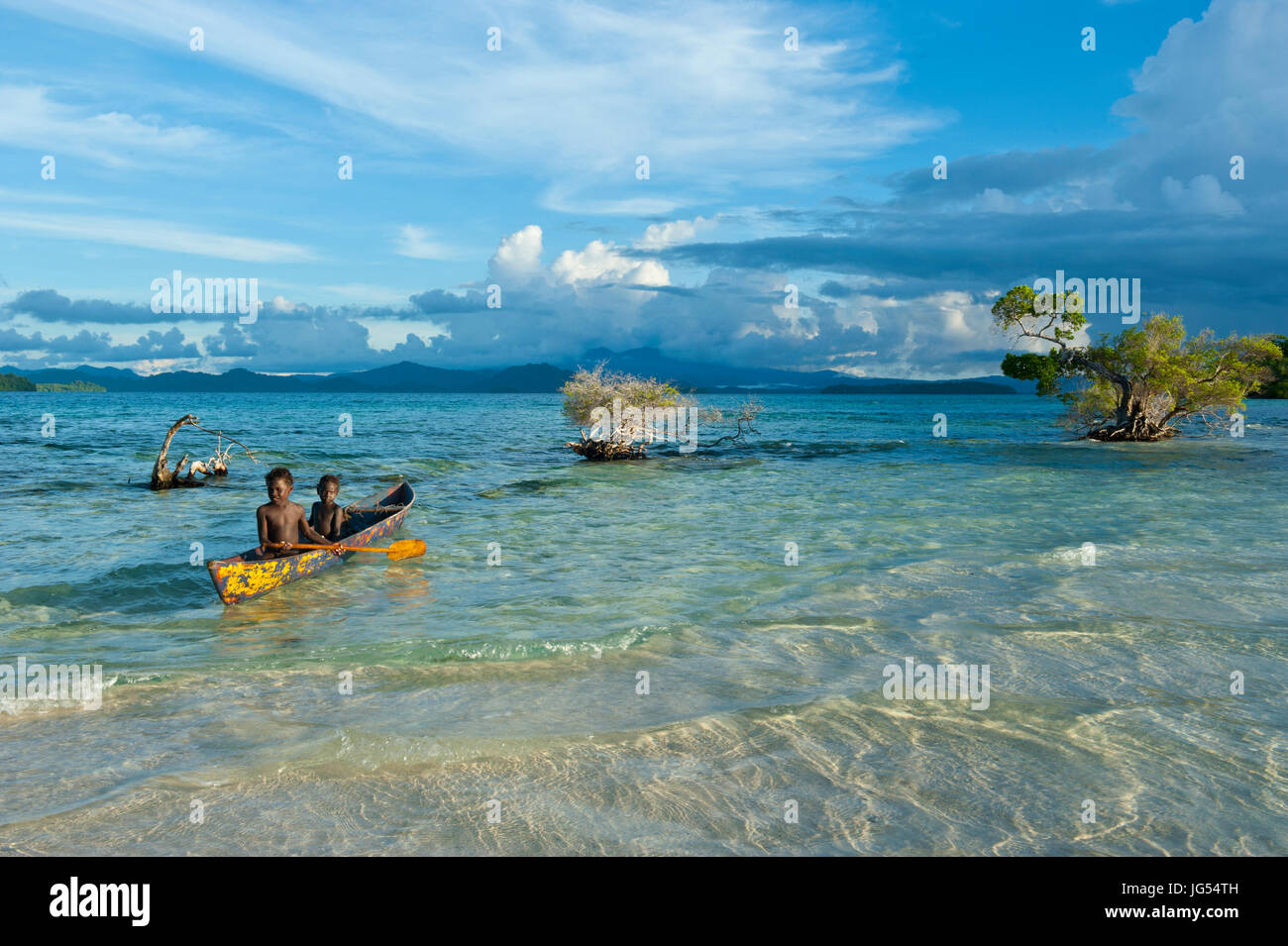 Young boys fishing in the Marovo Lagoon before dramatic clouds, Salomon Islands, Pacific Stock Photo