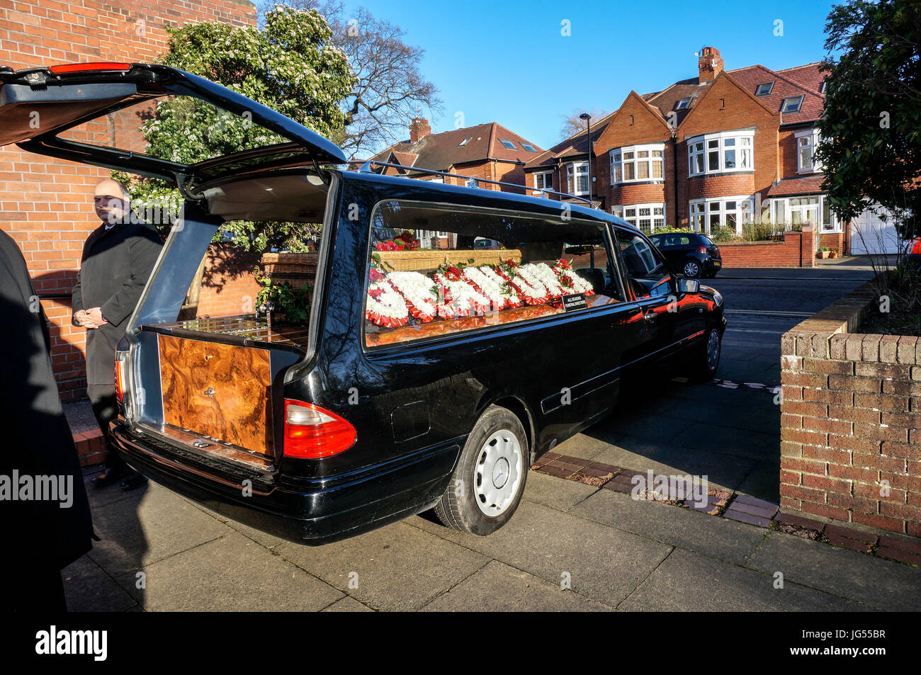 Long shot of a wicker coffin and floral tributes on display in a hearse, with the rear tailgate open. Jesmond, Newcastle, Tyne and Wear, England, UK. Stock Photo