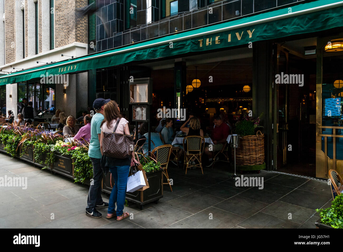 A Couple Look At The Menu Of The Ivy Soho Brasserie, Broadwick Street, London, UK Stock Photo