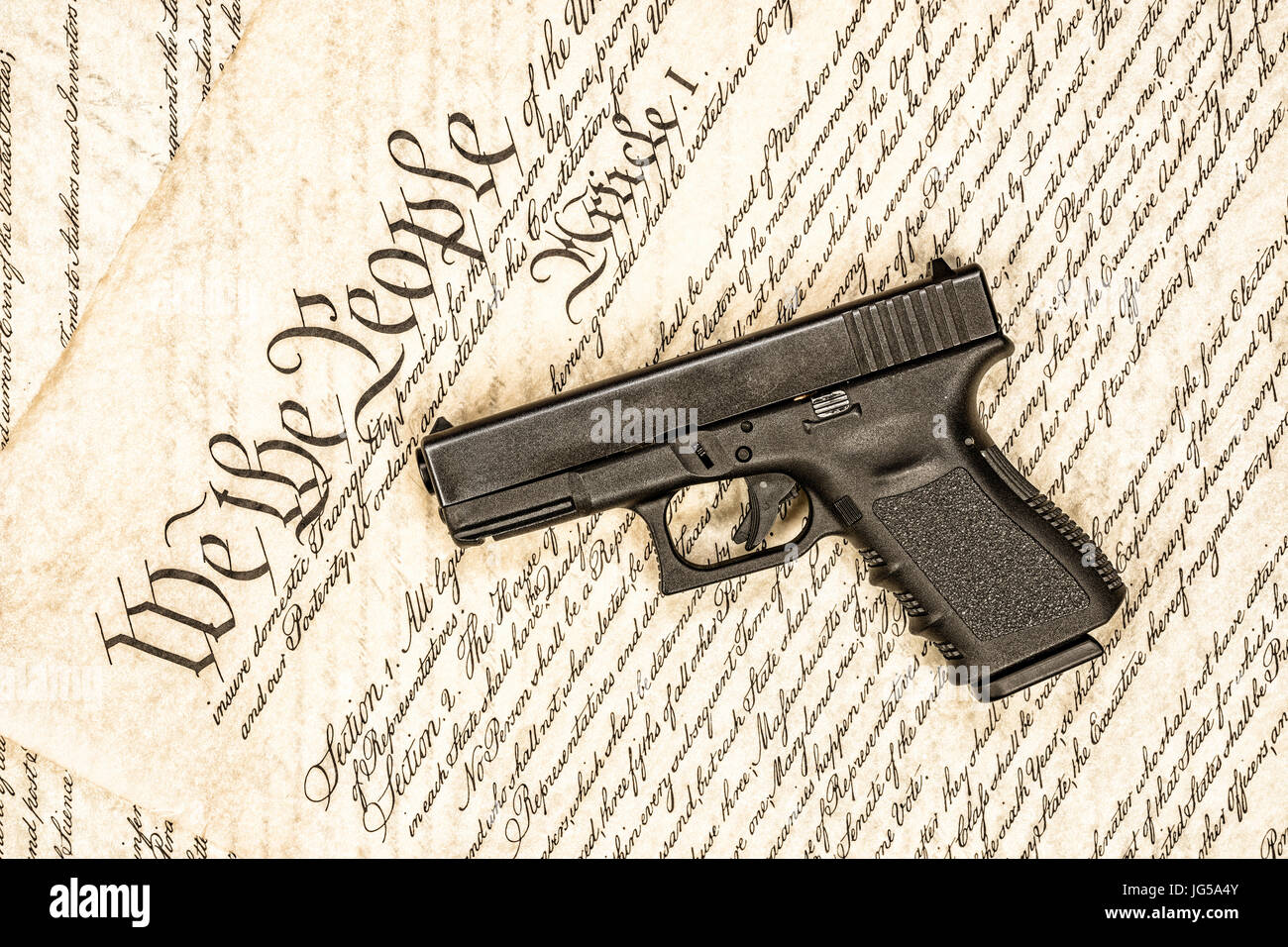 A handgun symbolizing gun rights while framed against the United States constitution. Stock Photo