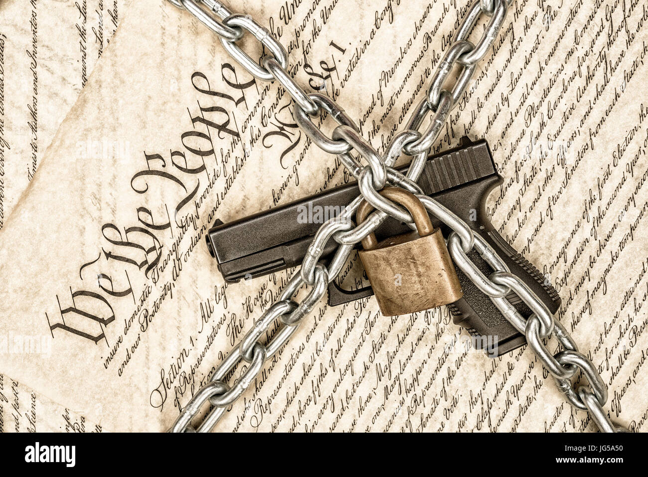 A locked handgun symbolizing gun rights while framed against the United States constitution. Stock Photo