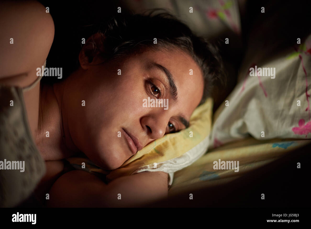 Portrait of young woman using tablet in bed. Girl reading from digital tablet at night Stock Photo