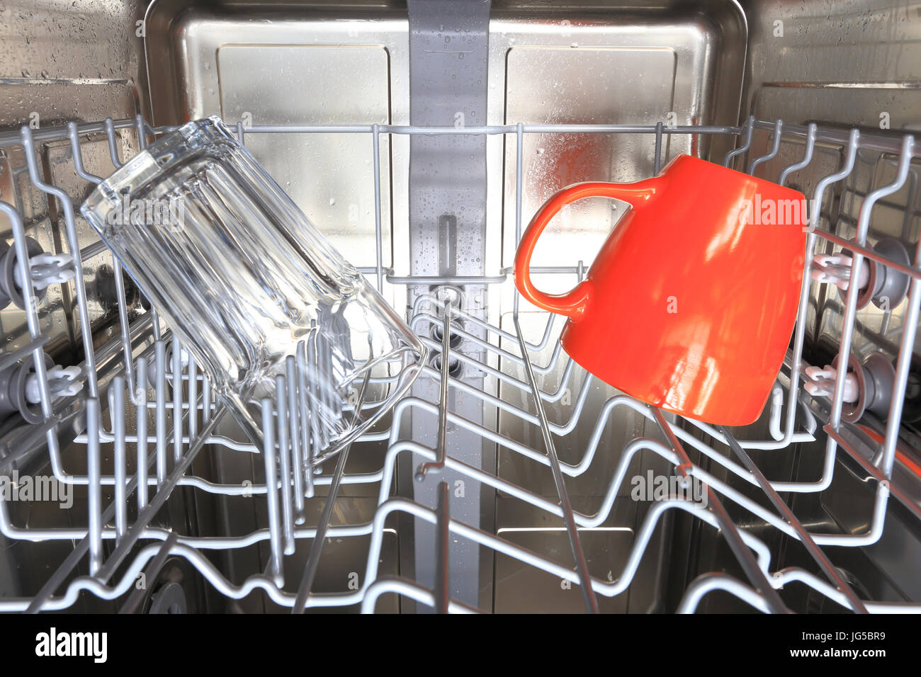 Wet stainless steel dishwasher interior. Cups in dishwasher machine