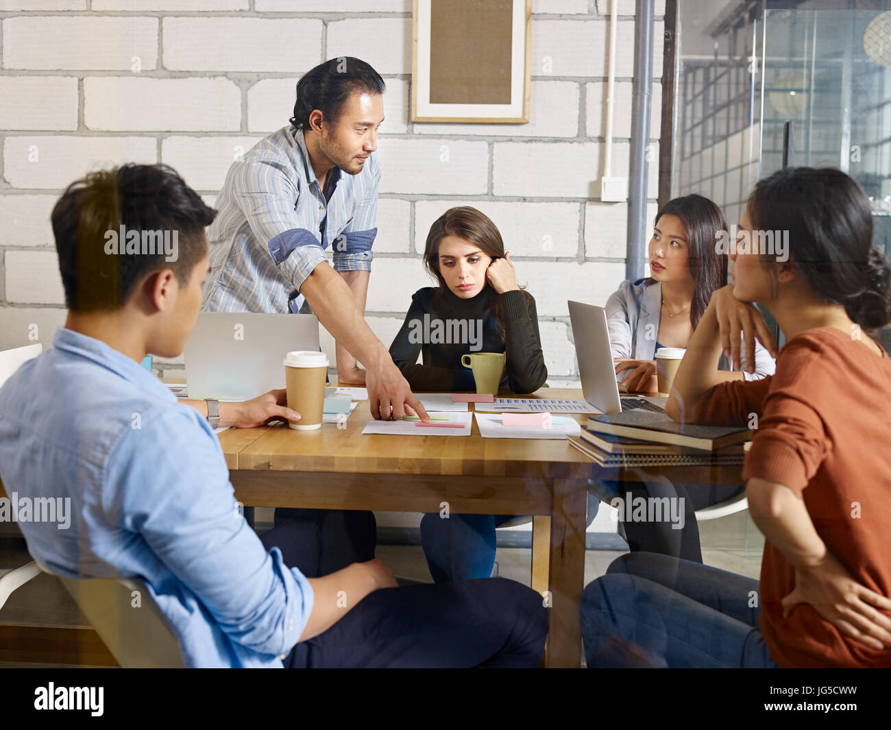 a team of multinational corporate people discussing business in glass meeting room. Stock Photo