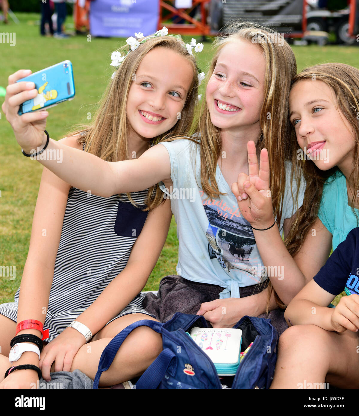 Three 10 and 11 year old girls taking a selfie at a summer fete, Milland, n...