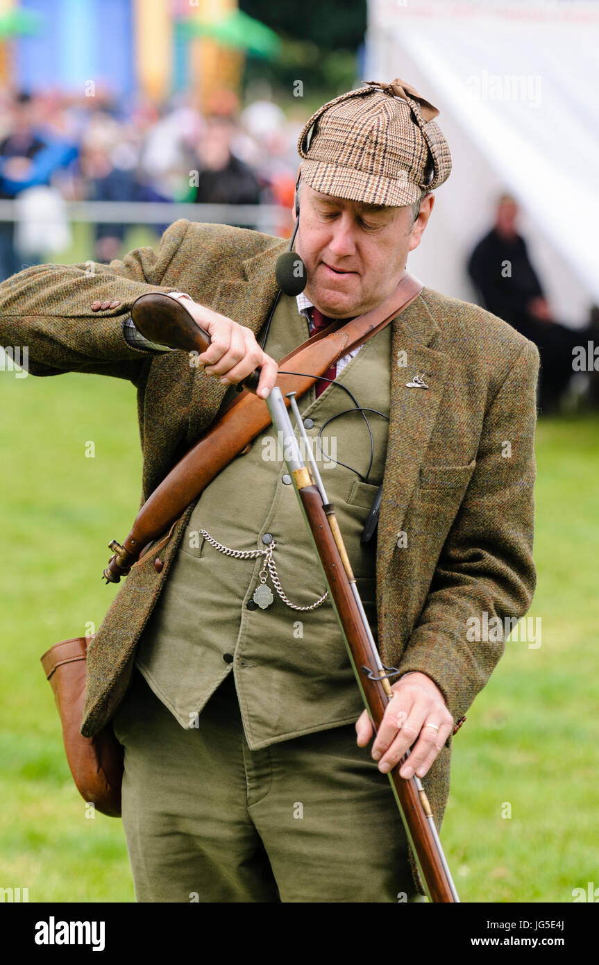 A man dressed in green Irish Lovat tweed jacket, deerstalker hat, waistcoat  and trousers, loads his flintlock rifle with gunpowder Stock Photo - Alamy