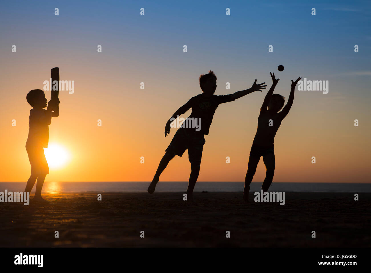 Children playing cricket on the beach as the sun goes down, Devon, UK Stock Photo