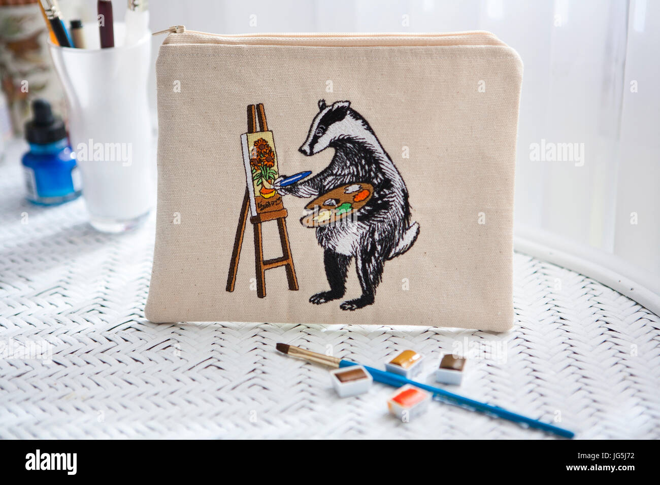 Art materials on desk with zipped pouch depicting an embroidered Badger painting Van Gogh's sunflowers Stock Photo