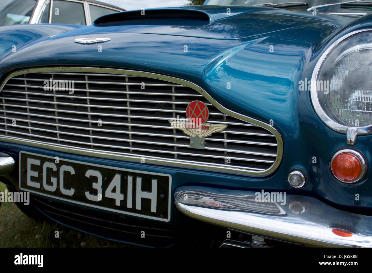 Aston Martin winged logo badge on grille of blue vintage car Stock Photo