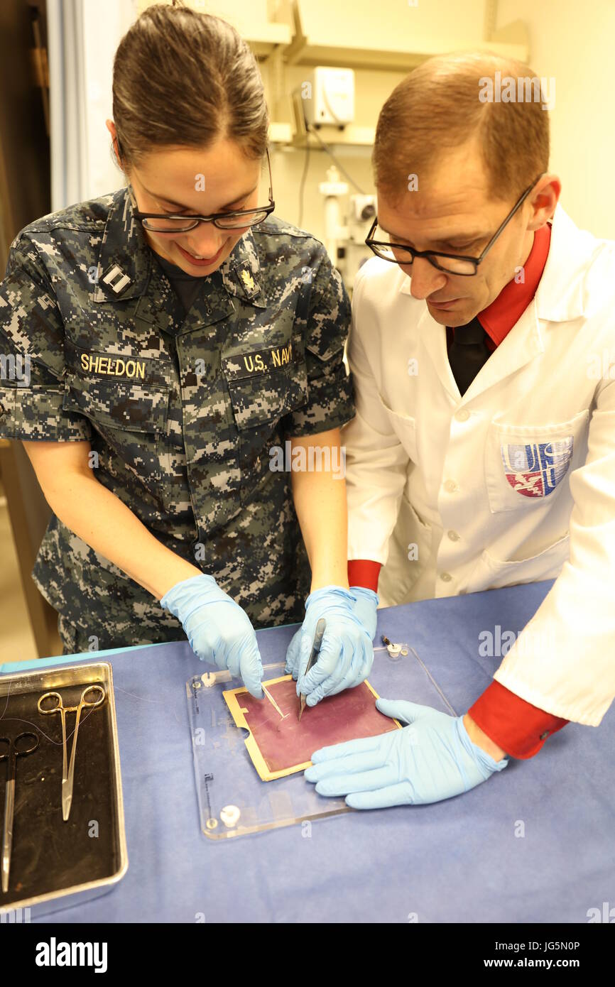 Uniformed Services University (USU) surgery instructor Ed Jones (right) observes as Navy Lt. (Dr.) Yarrow Sheldon (left) practices her suturing skills.  Lt. Sheldon participated in USU’s Surgery Boot Camp just prior to her graduation from the University’s F. Edward Hebert School of Medicine in May. Stock Photo