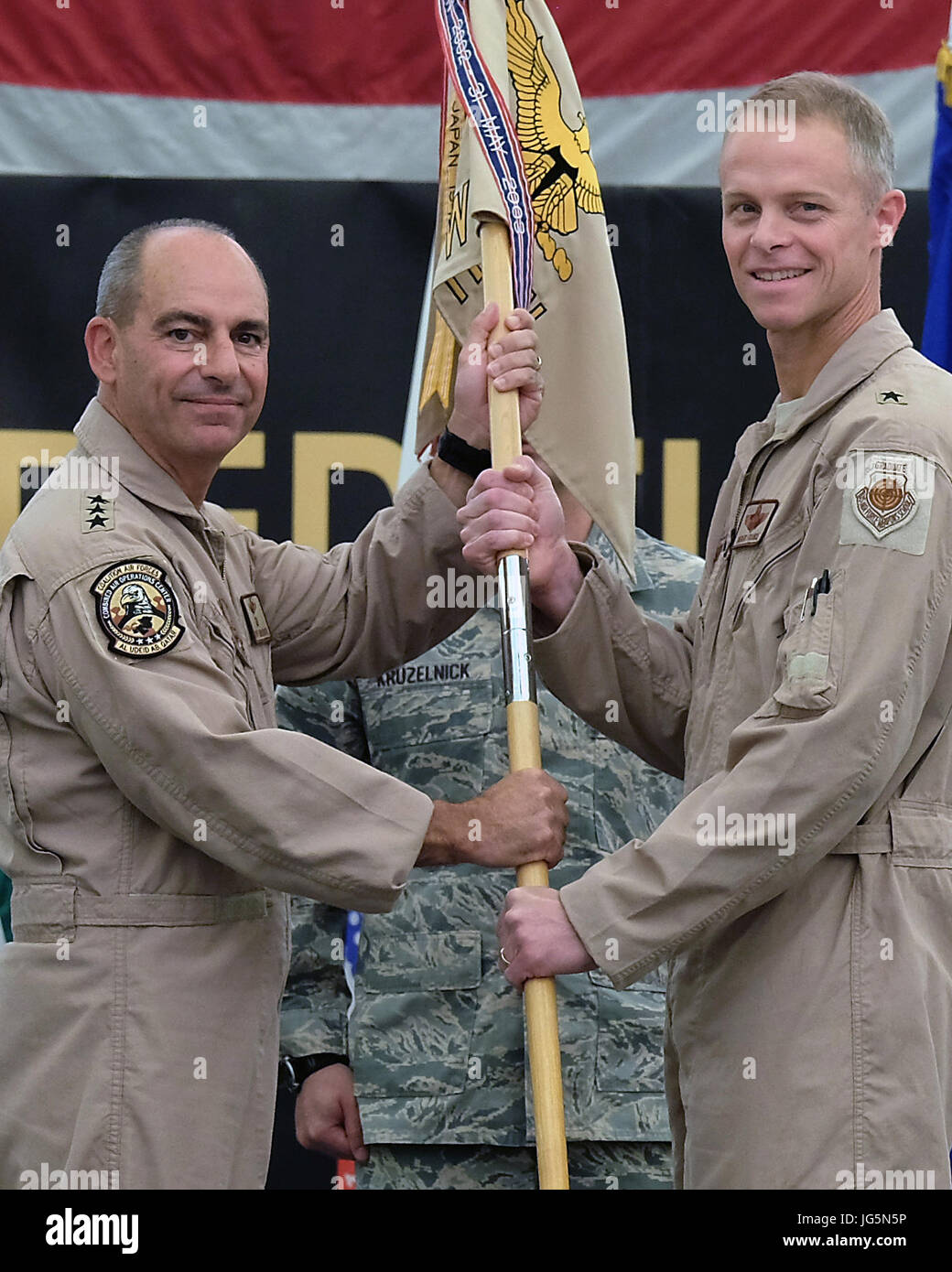 From right, Brig. Gen. Charles S. Corcoran, outgoing 380th Air  Expeditionary commander, passes the 380 AEW guidon to Lt. Gen. Jeffrey L.  Harrigian, U.S. Air Forces Central Command commander, during a change