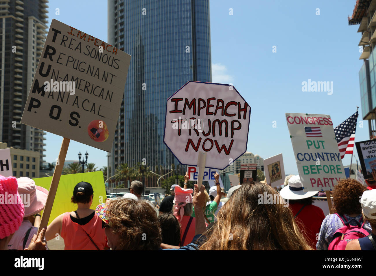 'Impeach Trump Now' and other signs held above the heads of protestors in the Impeachment March in San Diego, CA on July 2 as they move along street. Stock Photo