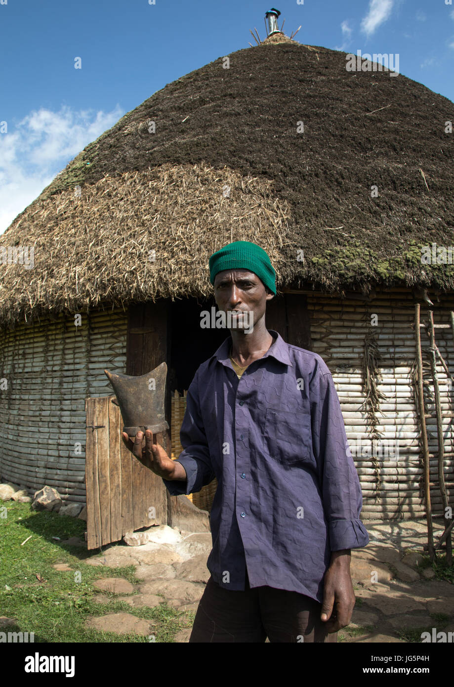 Gurage tribe man with his traditional wooden pillow in front of his house with tatched roof, Gurage Zone, Butajira, Ethiopia Stock Photo