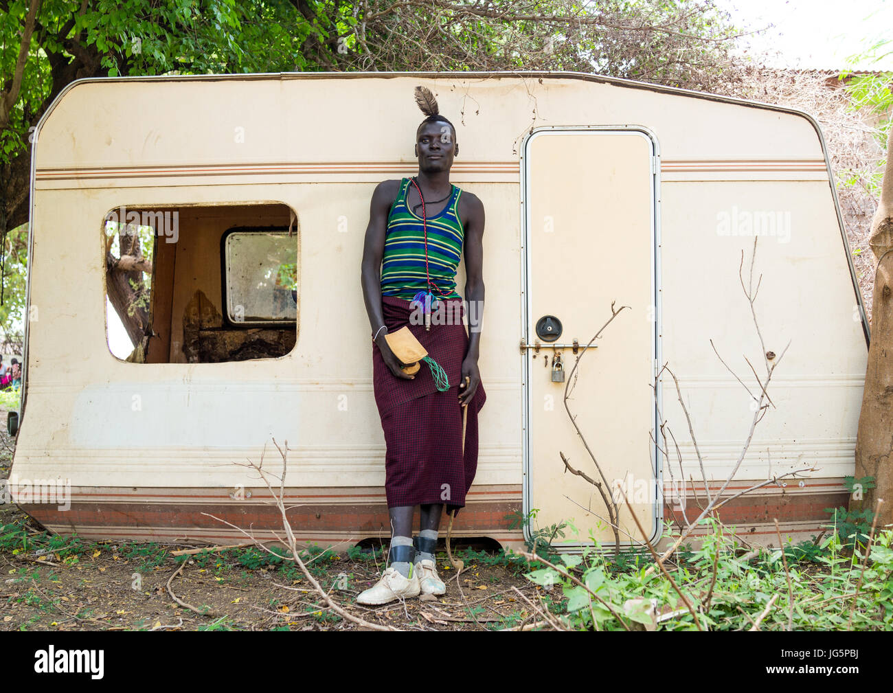 Sudanese Toposa tribe man refugee in front of an old abandonned caravan, Omo Valley, Kangate, Ethiopia Stock Photo