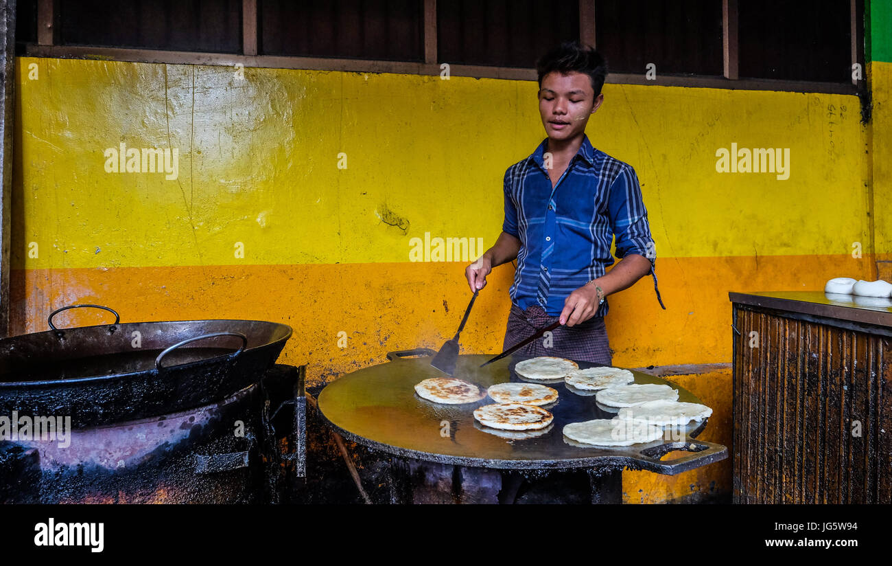 A man cooks chapatis at a street restaurant in downtown Yangon, Myanmar Stock Photo