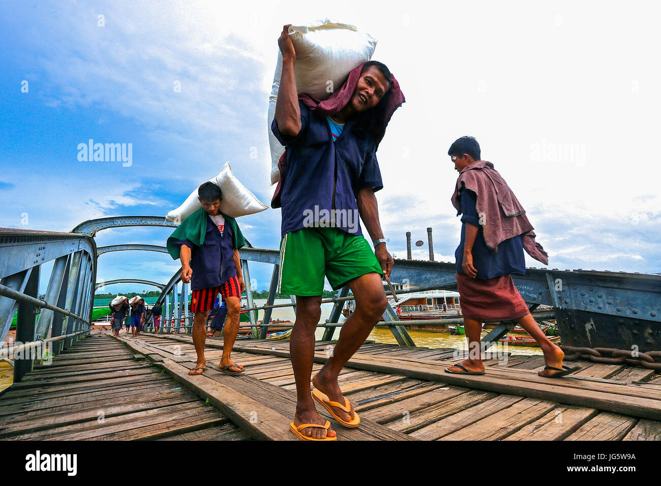 Workers unloading cargo from boats onto awaiting lorries at a dock in Yangon, Myanmar Stock Photo