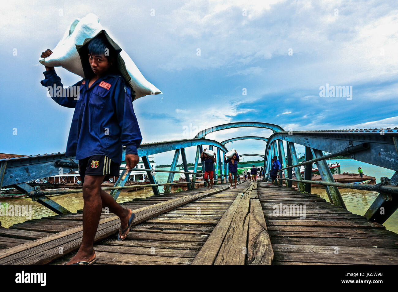 Workers unloading cargo from boats onto awaiting lorries at a dock in Yangon, Myanmar Stock Photo