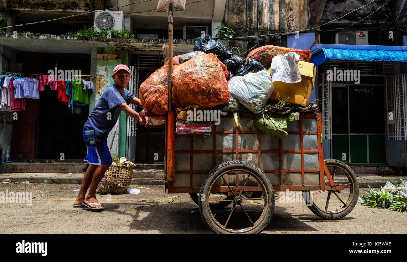 A man collects re-cyclable rubbish in a street in downtown Yangon, Myanmar Stock Photo