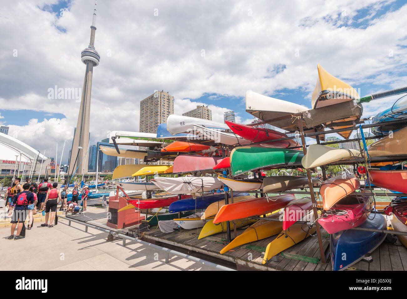 Toronto, Canada - 26 June 2017: Racks of brightly colored kayaks and canoes at Toronto waterfront in summer, with CN Tower in the background Stock Photo