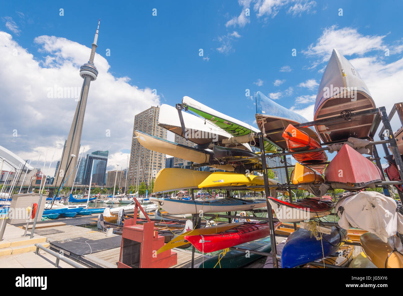 Toronto, Canada - 26 June 2017: Racks of brightly colored kayaks and canoes at Toronto waterfront in summer, with CN Tower in the background Stock Photo