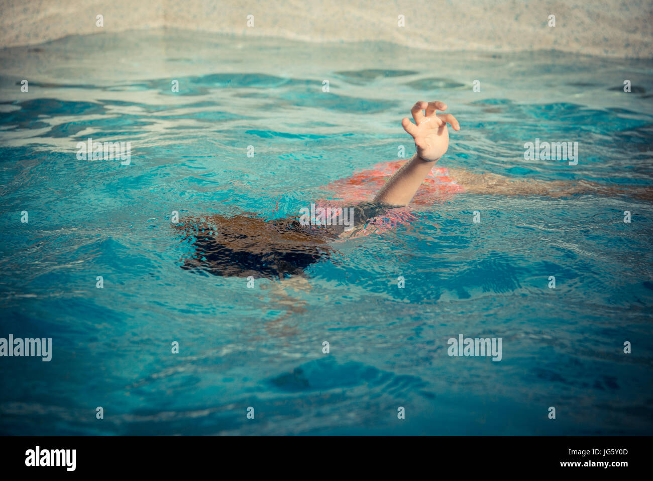 young little girl floating at swimming pool and showing hand calling for help when she playing
