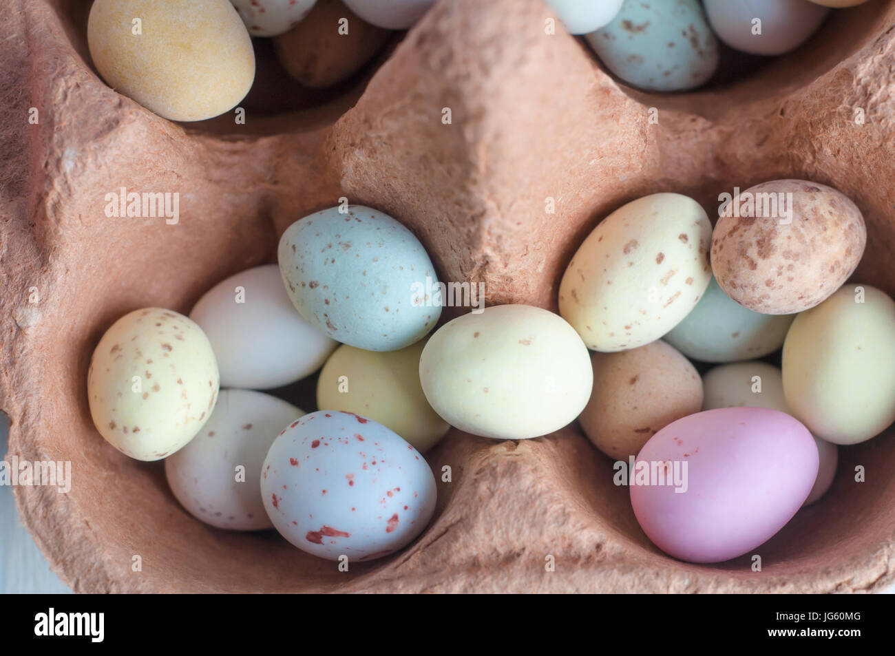 Overhead close-up view of egg shaped sweets (candies) piled into the compartments of an egg carton. Stock Photo