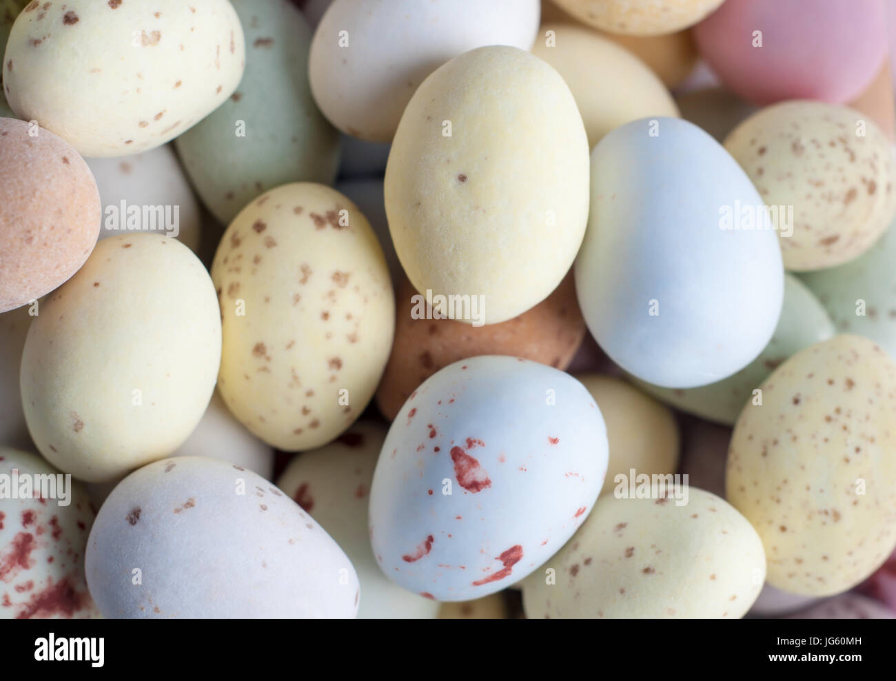Overhead close up (macro) of a pile of Egg shaped Easter sweets (candies) in pastel shades. Stock Photo