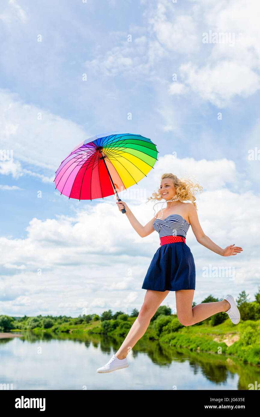 Girl jumping with a colorful umbrella Stock Photo - Alamy