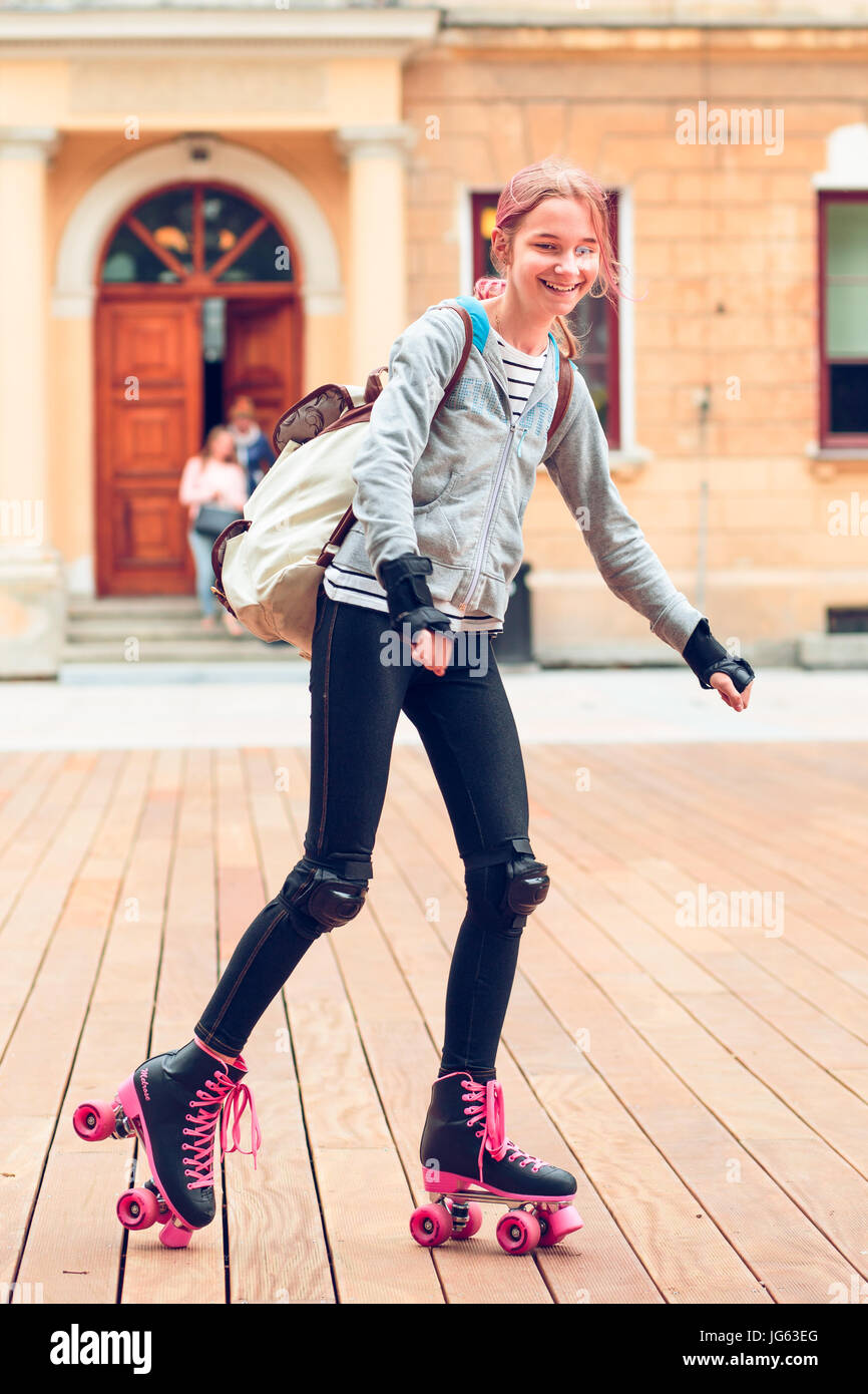 Young girl roller skating in a town spending time actively outdoors on summer day Stock Photo