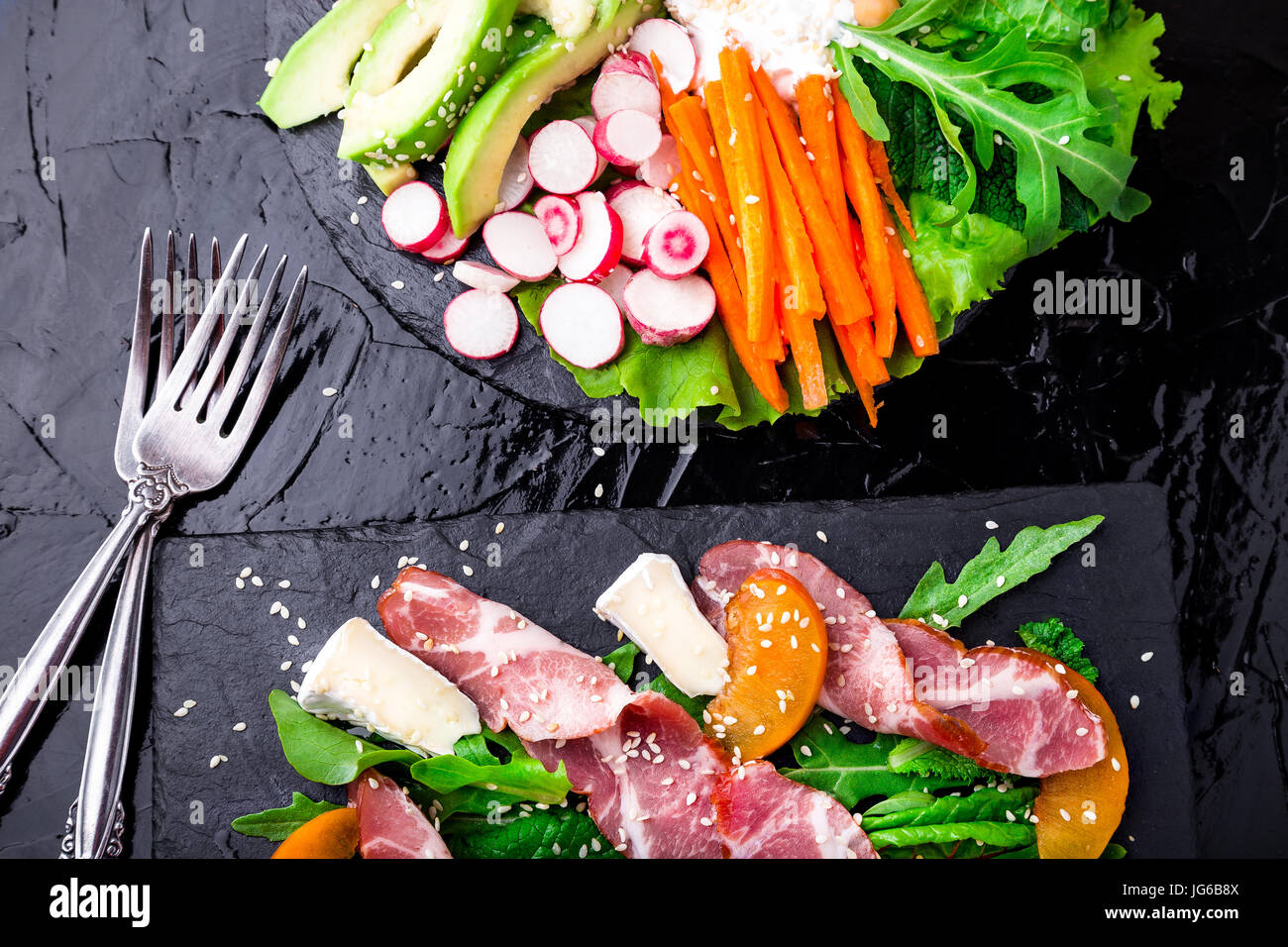 Two different salads om black stone slate. Vegan salad. Meat salad