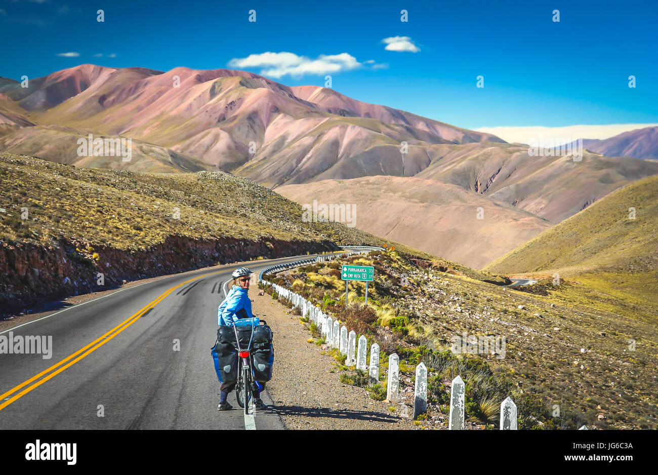 Woman cycling on the empty road in the remote part of north west Argentina Stock Photo