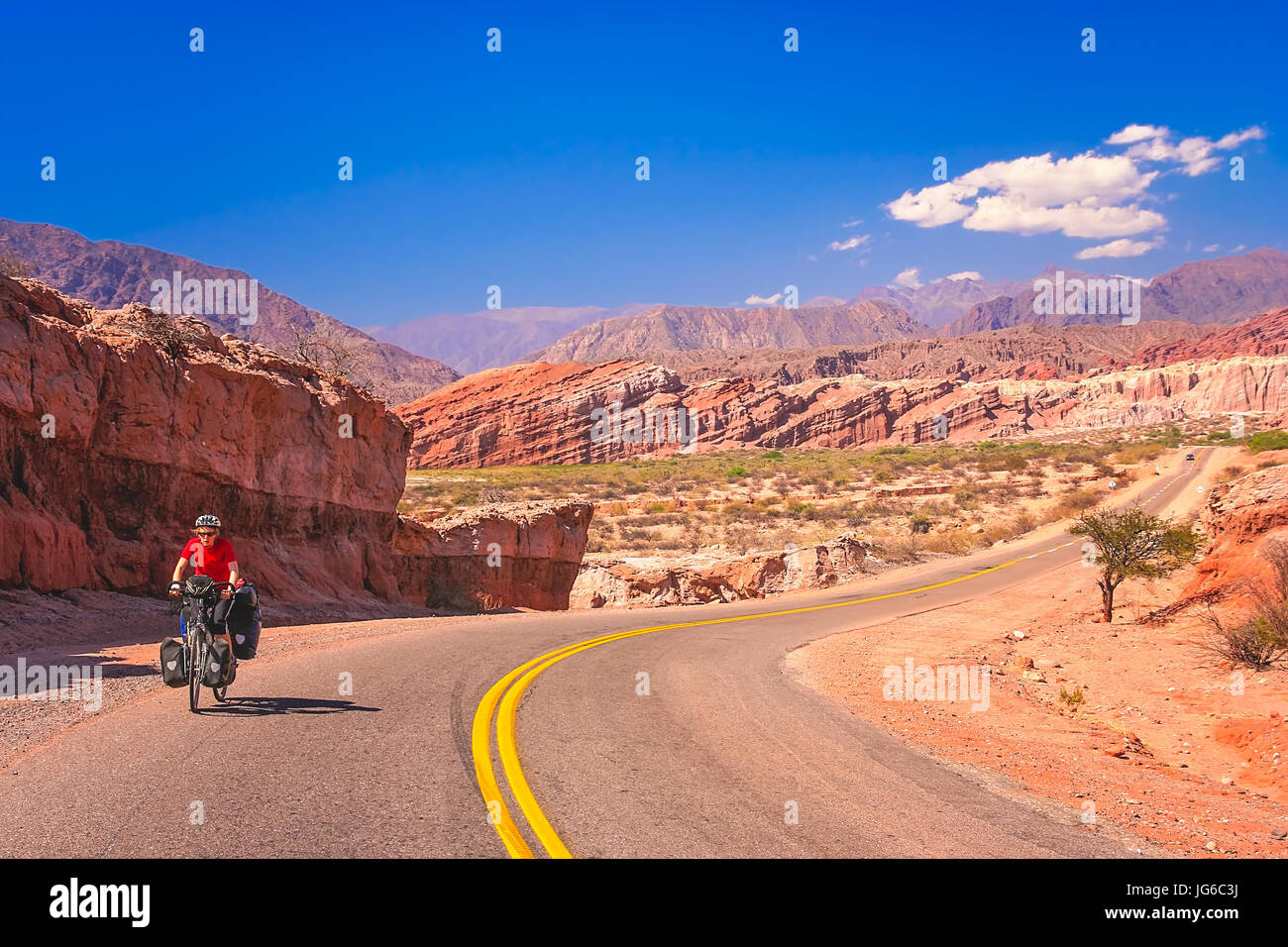 Woman cycling on the empty road to Cafayate in the remote part of north west Argentina Stock Photo