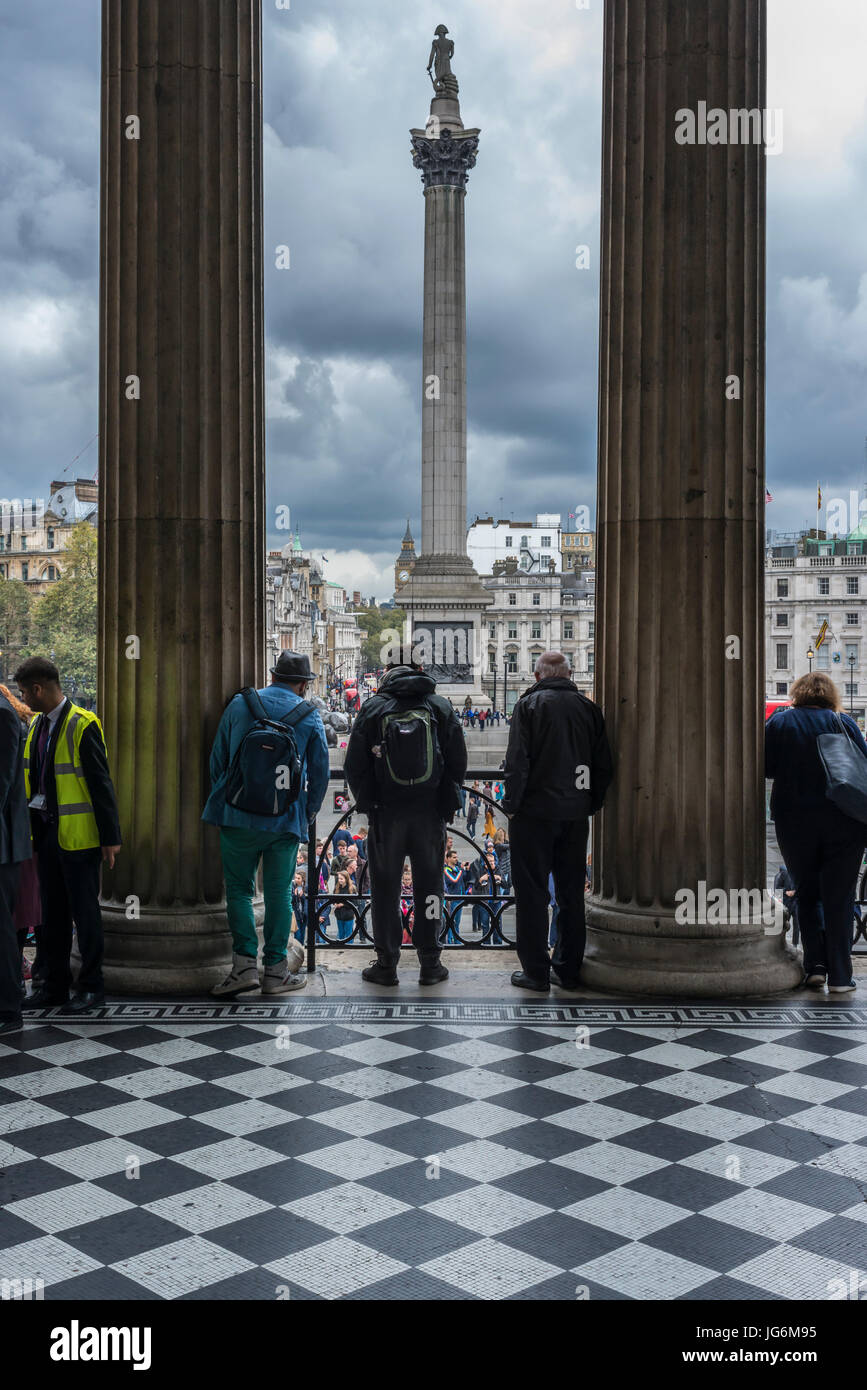 Tourists looking down Trafalgar Square from the balcony of National Gallery Stock Photo