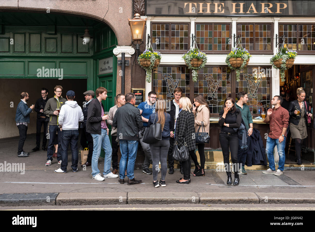 People having conversation with drinks in hand outside The Harp Pub, London, UK Stock Photo