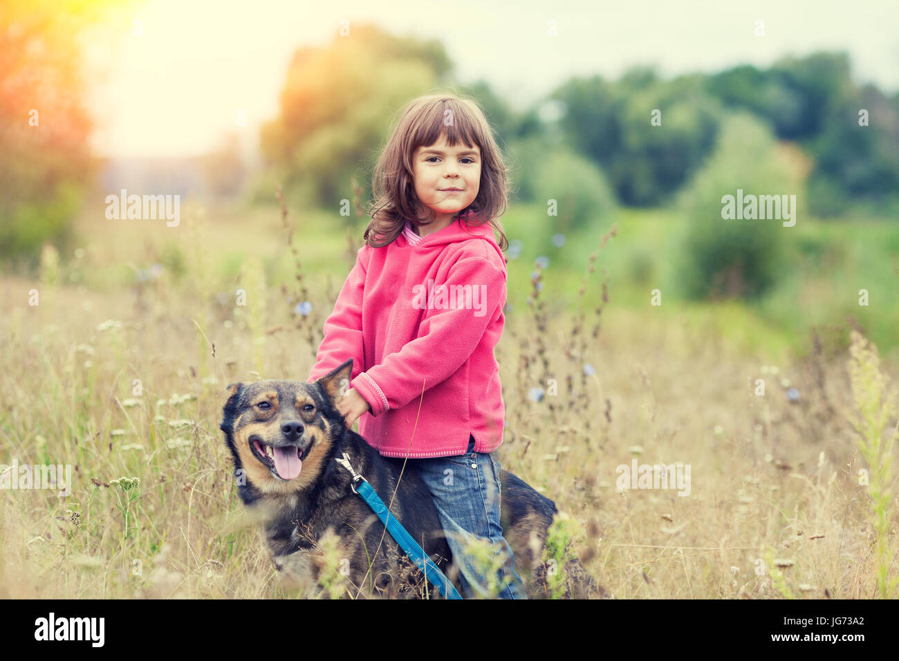 Happy little girl walking with dog on the field Stock Photo - Alamy