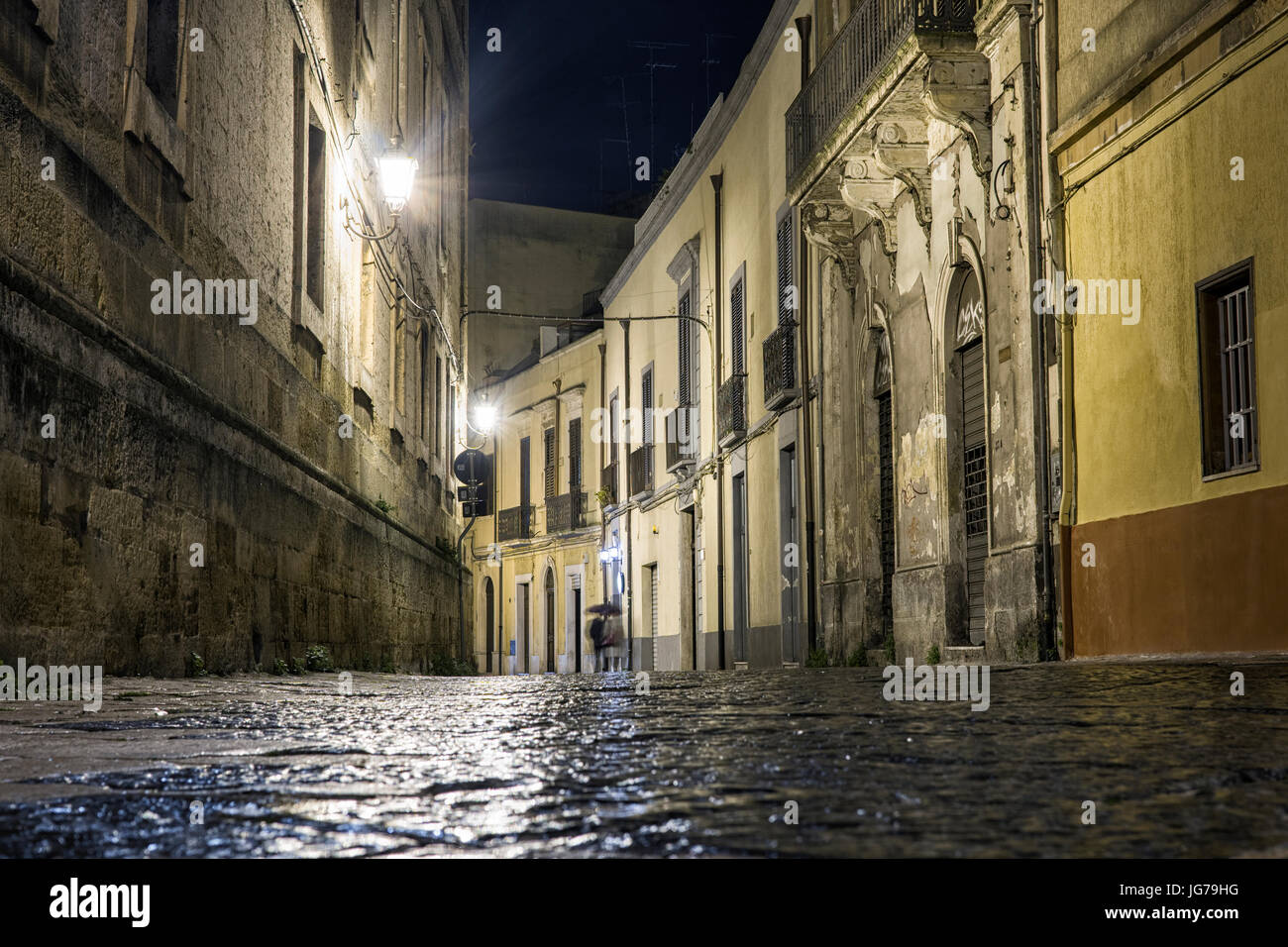 Street in Brindisi by night with disappearing couple, Puglia, Italy Stock Photo