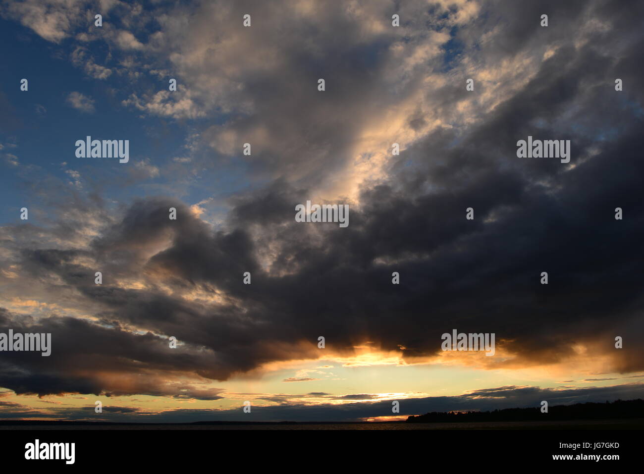Glowing abyss in the cloudy sky at sunset over the lake Stock Photo