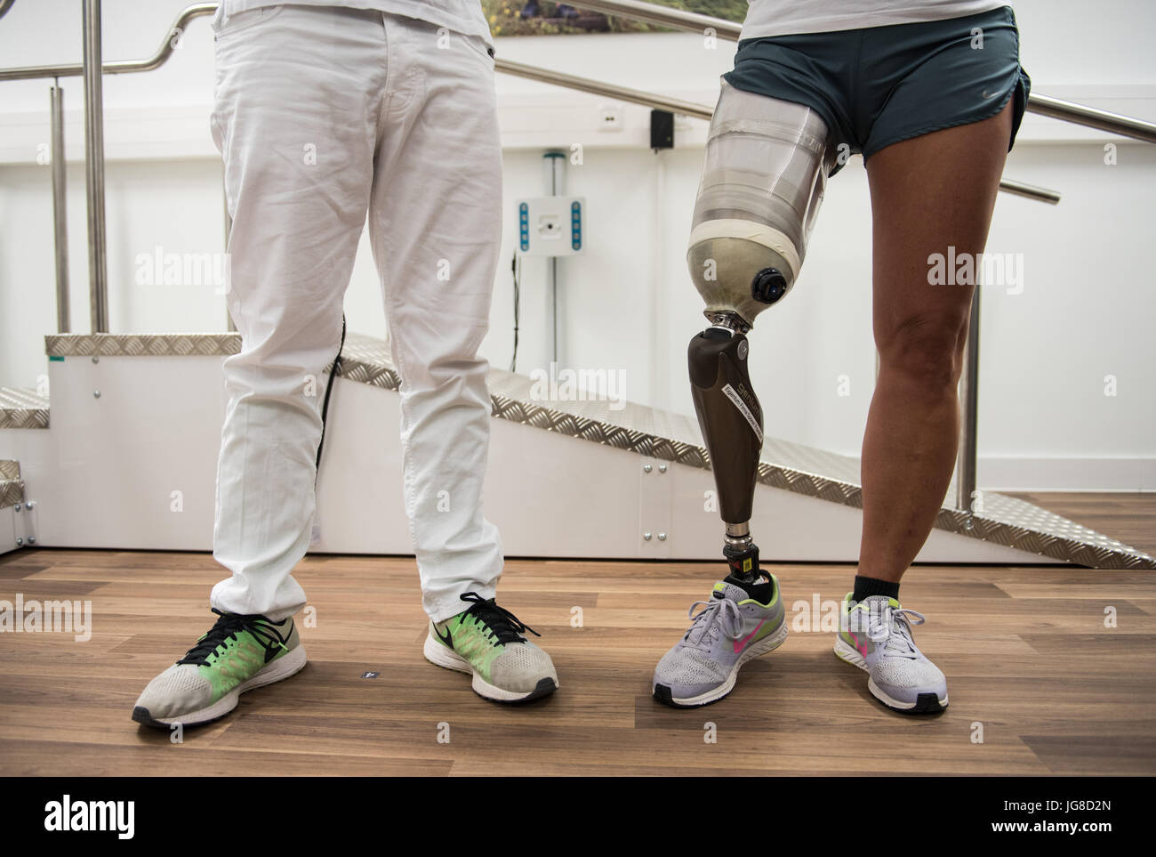 An orthopaedic technician stands next to a woman with a leg prothesis