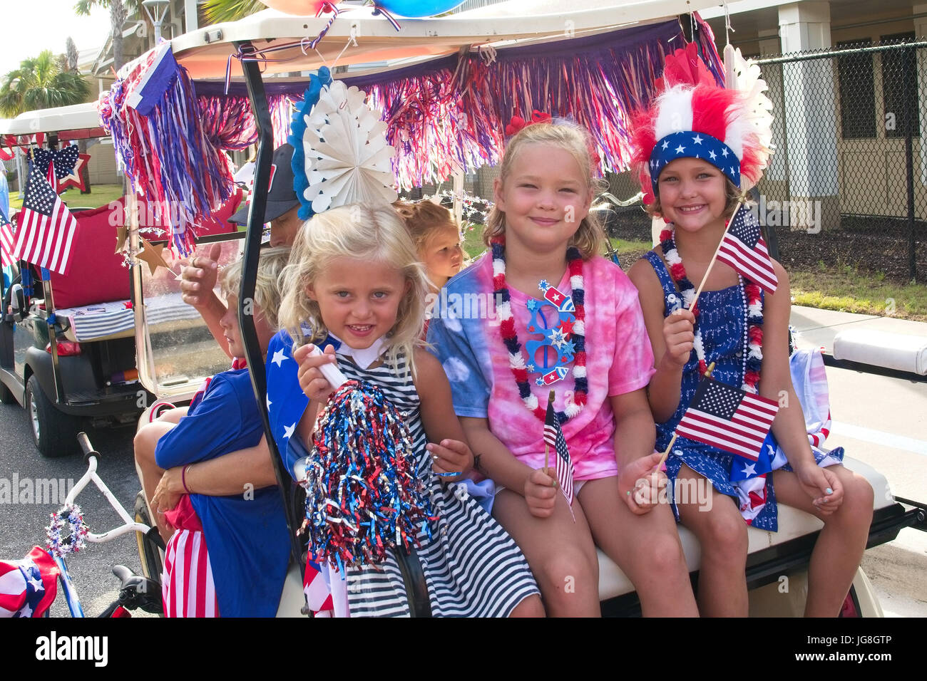 Sullivan's Island, South Carolina, USA. 4th July, 2017. Young girls smile as they ride along in a golf cart decorated in patriotic bunting during the annual Sullivan's Island Independence Day parade July 4, 2017 in Sullivan's Island, South Carolina. The tiny affluent sea island hosts a bicycle and golf cart parade through the historic village. Credit: Planetpix/Alamy Live News Stock Photo