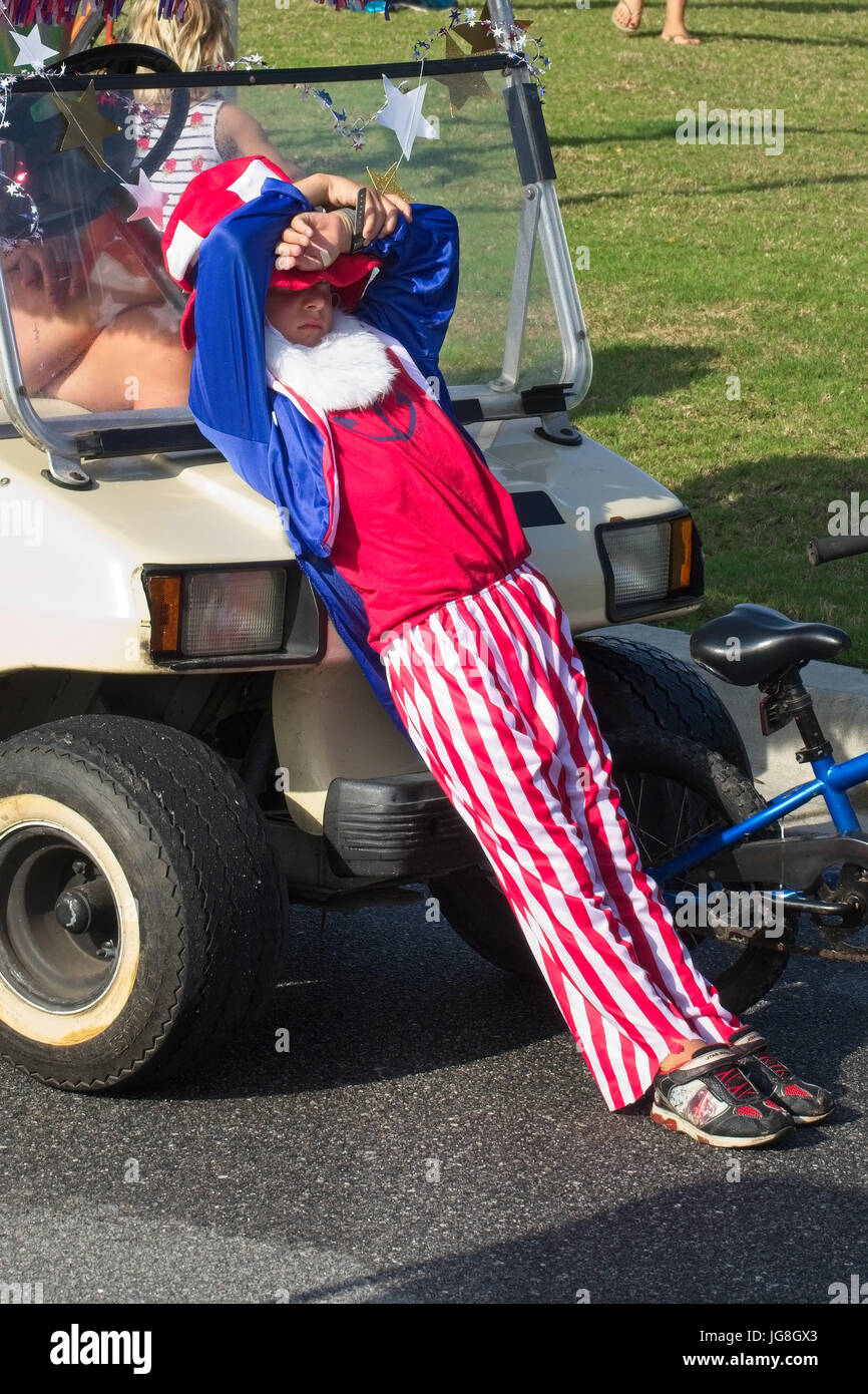 Sullivan's Island, South Carolina, USA. 4th July, 2017. A young boy dressed as Uncle Sam rests in 90-degree heat during the annual Sullivan's Island Independence Day parade July 4, 2017 in Sullivan's Island, South Carolina. The tiny affluent sea island hosts a bicycle and golf cart parade through the historic village. Credit: Planetpix/Alamy Live News Stock Photo