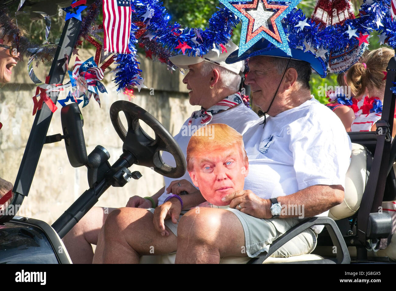 Sullivan's Island, South Carolina, USA. 4th July, 2017. An elderly man rides along with a Donald Trump mask during the annual Sullivan's Island Independence Day parade July 4, 2017 in Sullivan's Island, South Carolina. The tiny affluent sea island hosts a bicycle and golf cart parade through the historic village. Credit: Planetpix/Alamy Live News Stock Photo