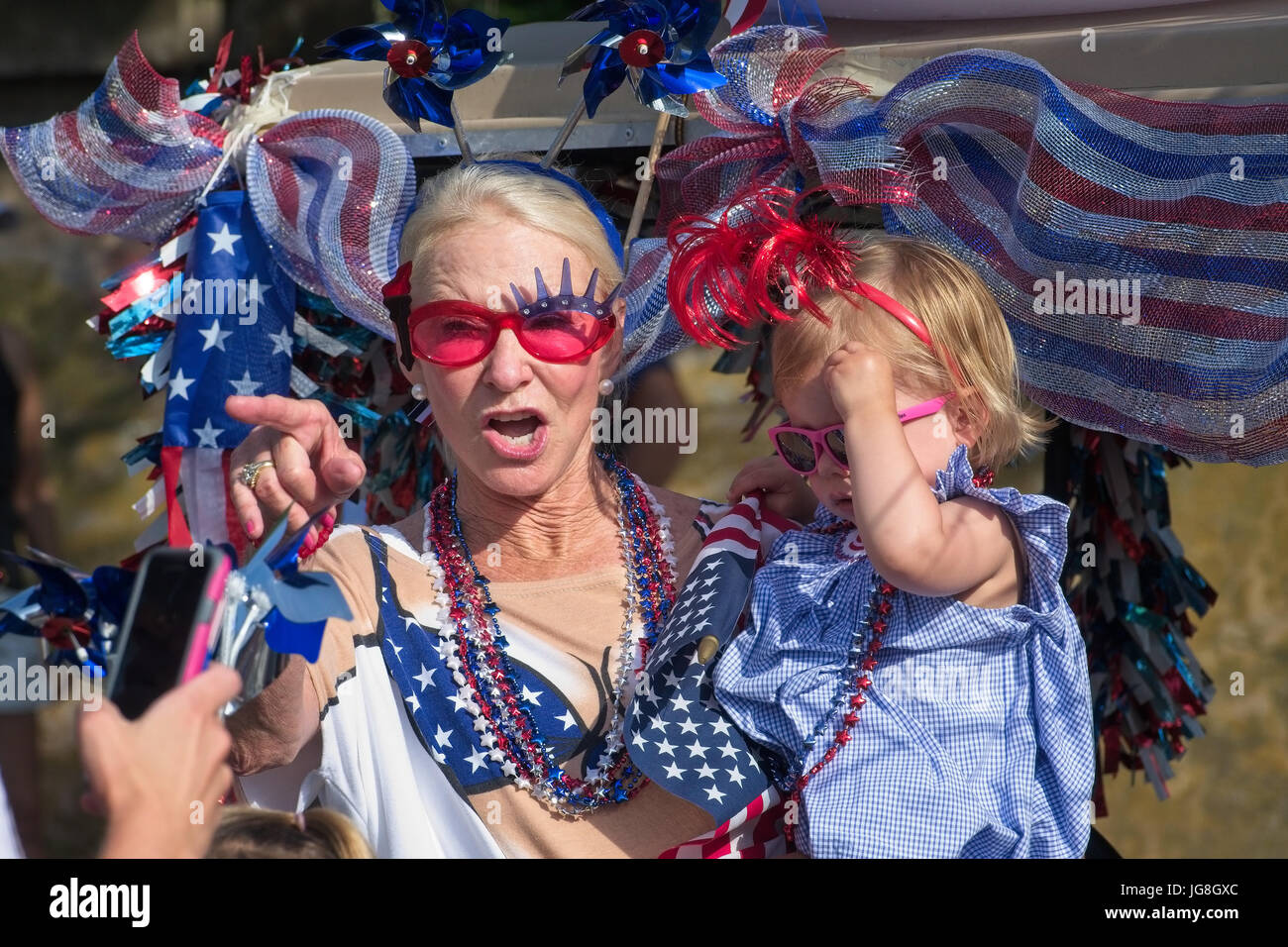 Sullivan's Island, South Carolina, USA. 4th July, 2017. A grandmother holds her young granddaughter during the annual Sullivan's Island Independence Day parade July 4, 2017 in Sullivan's Island, South Carolina. The tiny affluent sea island hosts a bicycle and golf cart parade through the historic village. Credit: Planetpix/Alamy Live News Stock Photo