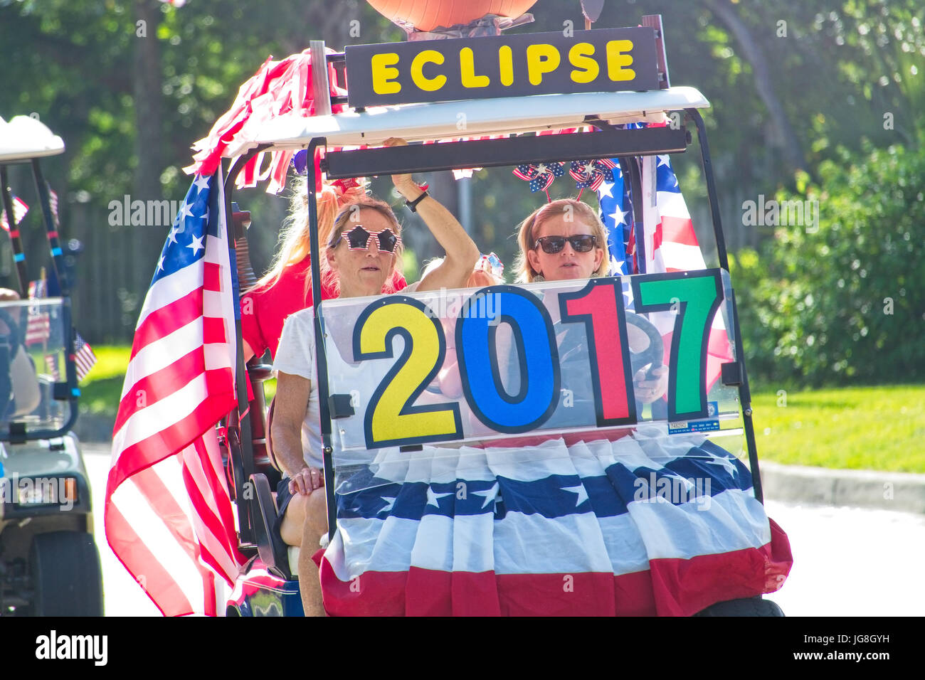 Sullivan's Island, South Carolina, USA. 4th July, 2017. A family rides a golf cart celebrating the upcoming solar eclipse during the annual Sullivan's Island Independence Day parade July 4, 2017 in Sullivan's Island, South Carolina. The solar eclipse will be visible from the Charleston area for the longest period in the continental USA before moving over the Atlantic Ocean. Credit: Planetpix/Alamy Live News Stock Photo