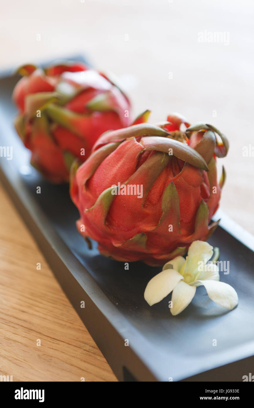 Fresh pitaya / dragon fruit on a table setting with white orchid Stock Photo