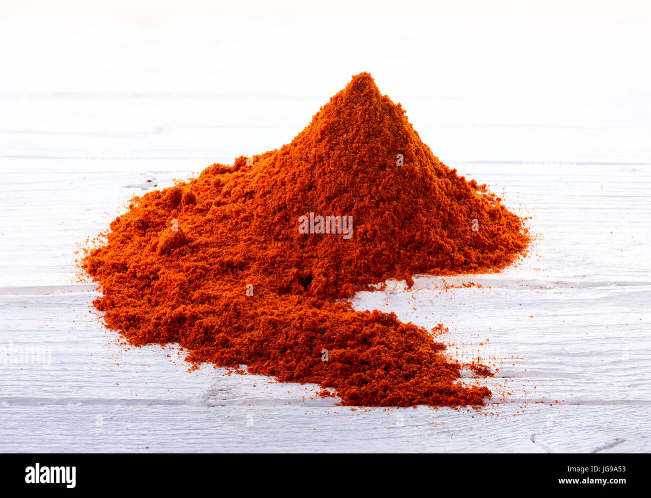 Heap of bell pepper sweat paprika powder on white wooden background. Stock Photo