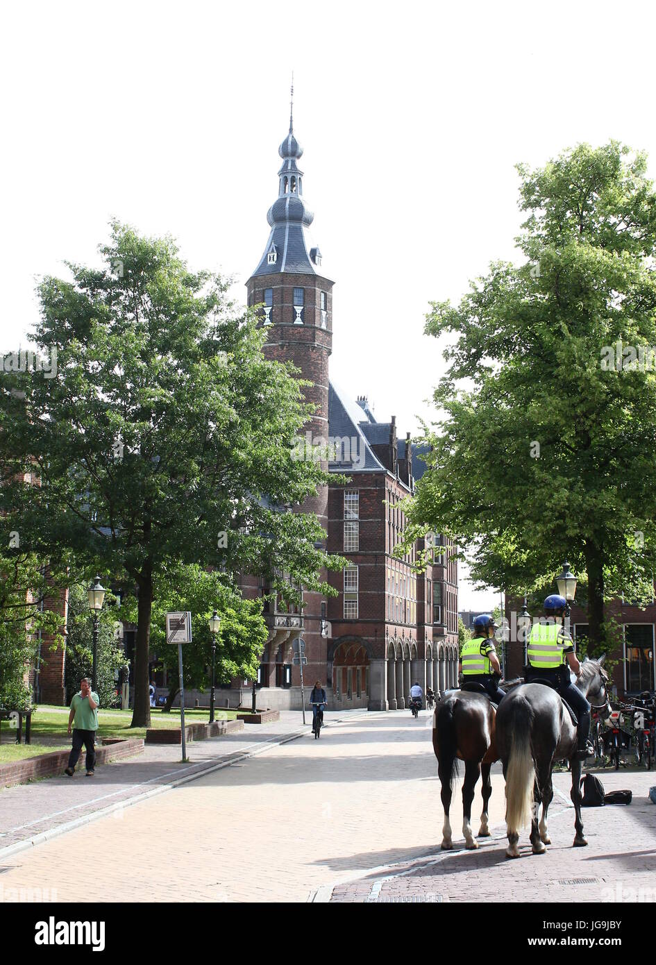 Dutch Policemen on horseback patrolling the streets of the inner city of Groningen, Netherlands at Martinikerkhof. Stock Photo