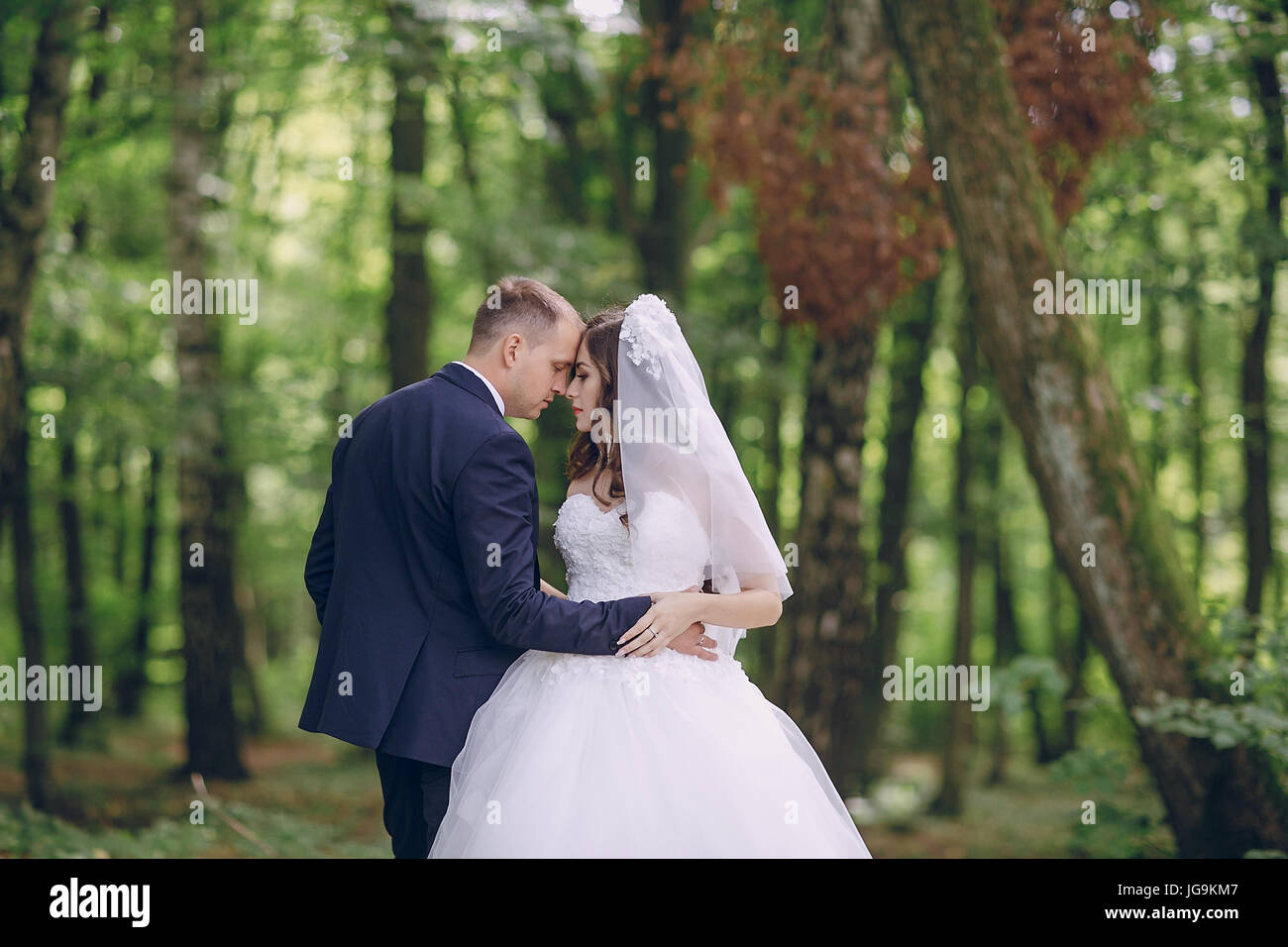 bride and groom walking in a green forest Stock Photo - Alamy